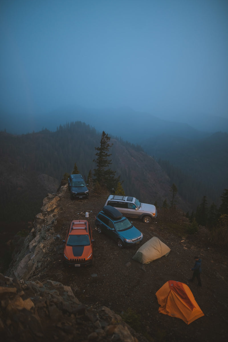 Four SUVs & two tents perched on a misty mountain cliff, overlooking forests. Rugged off-road camping is a unique adventure, unlike an RV rental. — photo 20