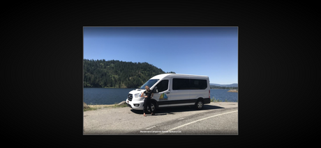 Enjoy the outdoors! White Wandervans campervan RV rental parked by a lake, with mountains and a person.