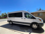 This spacious white Ford Transit van, ready for your next RV rental journey, is parked on a sunlit driveway.