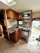 Explore this RV rental's compact kitchen with a sink, stove, microwave, and fold-out counter for efficient space use.