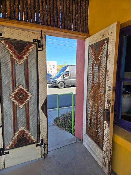 Open, patterned wooden doors frame a gray van on a sunny street, ready for your RV rental trip.