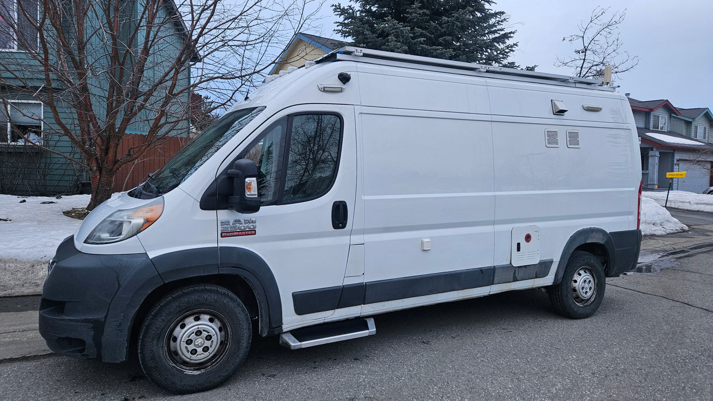 Customized white Ram ProMaster camper van parked on a snowy street, ready for your rv rental adventure.