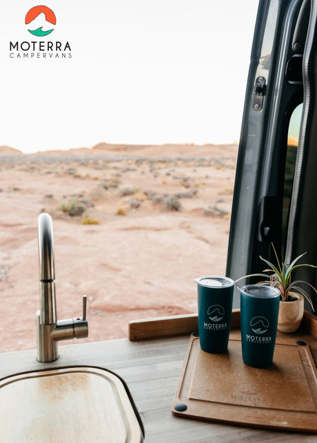 RV rental campervan interior: kitchen with sink, Moterra mugs, cutting board, and desert view. Explore in comfort!