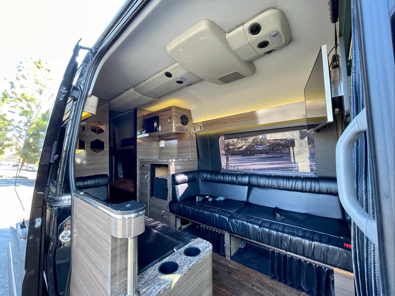 Spacious luxury RV rental interior with black leather seating, wood panels, and modern amenities for comfortable travel. — photo 2