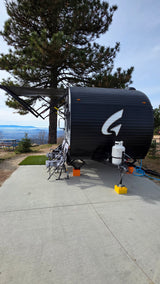 Enjoying the view from an RV rental: a black travel trailer with an extended awning parked at a scenic mountain campsite.