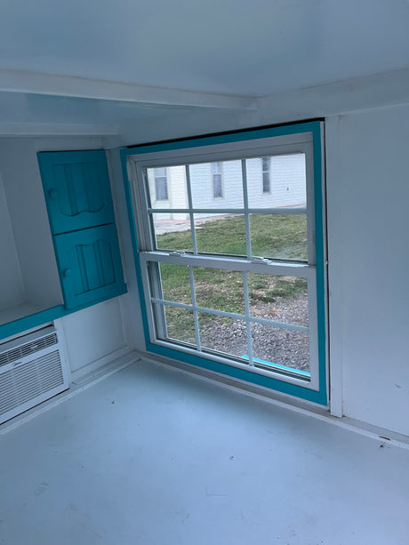 Cozy RV rental interior with light blue accents, white walls, functional cabinetry, and window AC unit.
