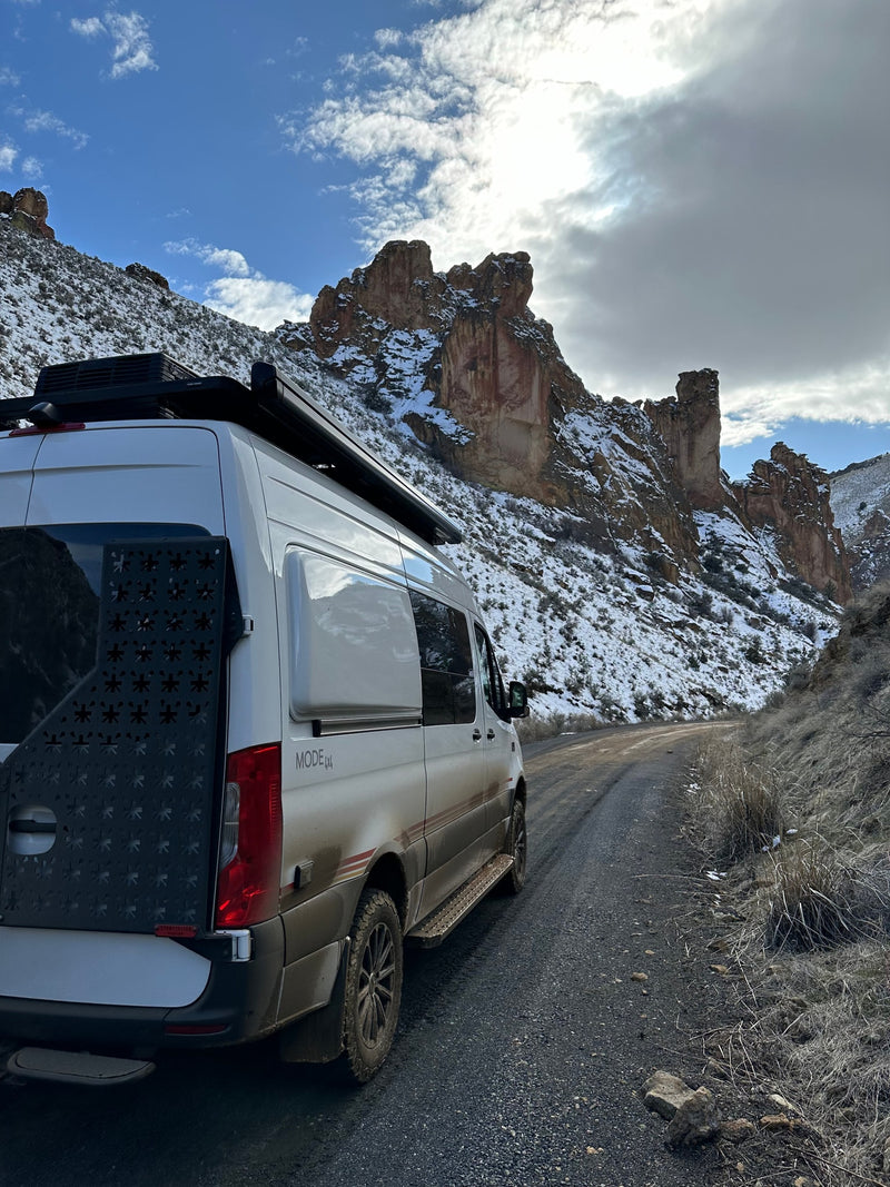 A rugged rv rental van on a snowy mountain dirt road — photo 1
