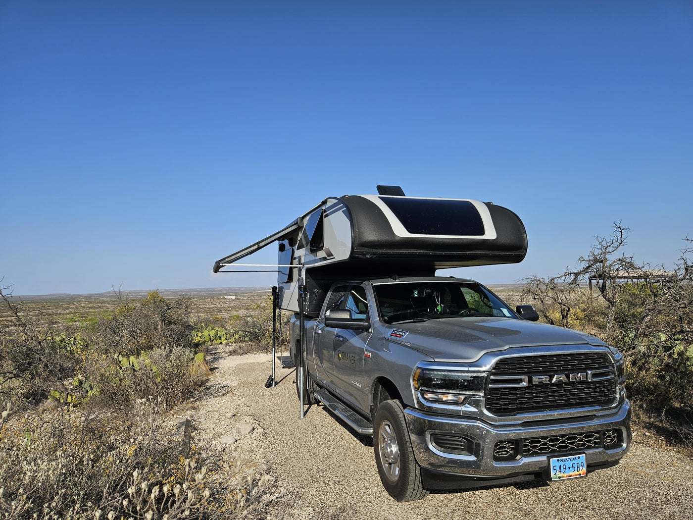 Graner RV rental truck camper parked in a sunny desert setting with an extended awning, ready for outdoor adventure. — photo 10