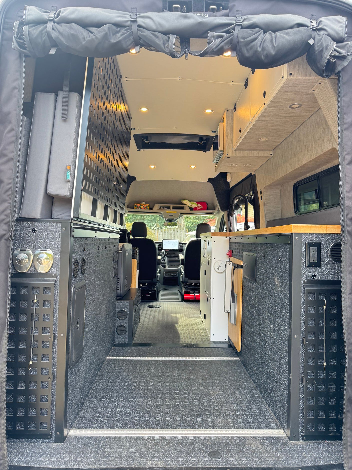 Inside a custom RV rental camper van: modular storage, a functional kitchen, & versatile living space from rear doors.