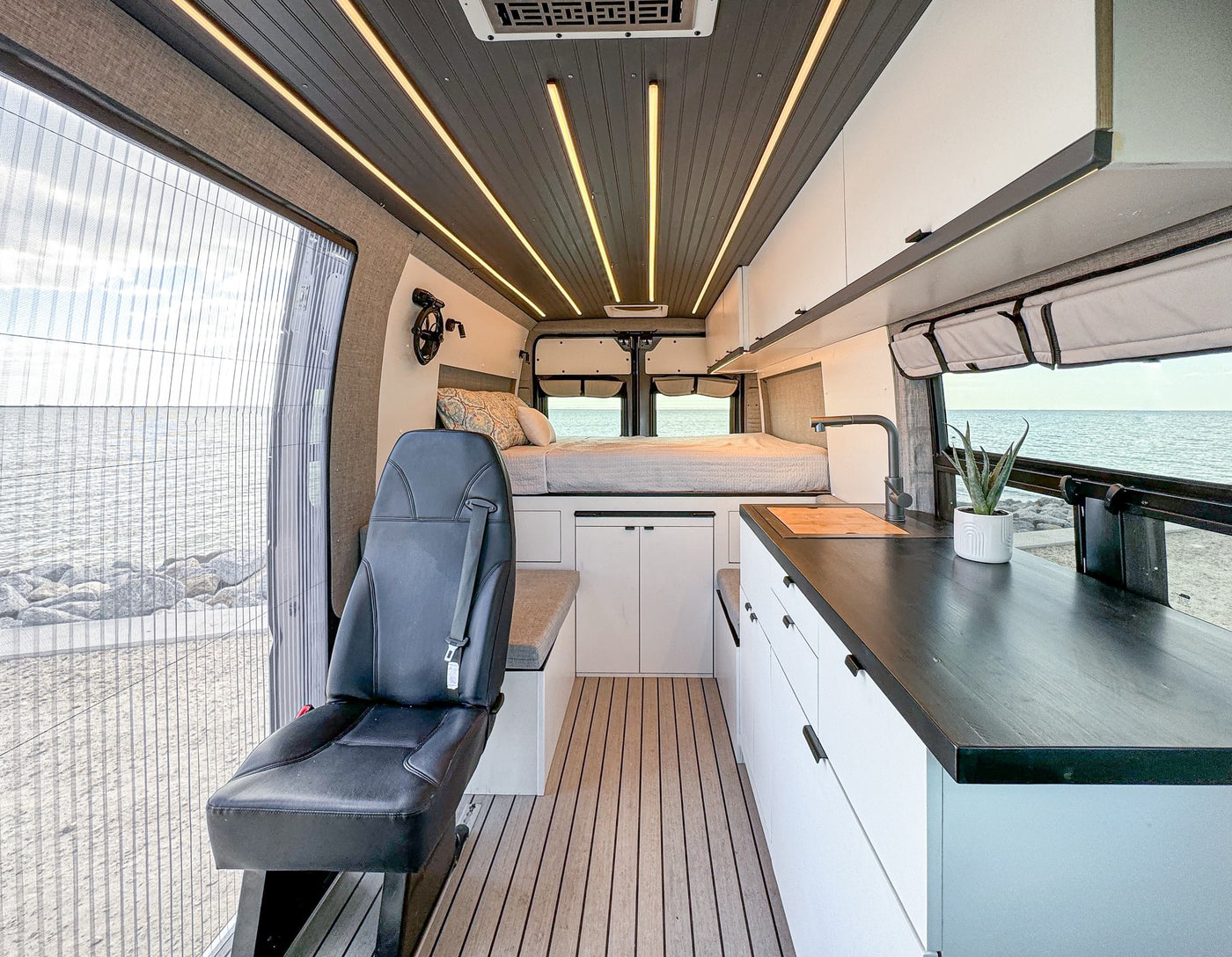 and chairs by the sea. Woman & boy high-fiving.|Spacious RV rental camper van interior with ocean view — photo 3