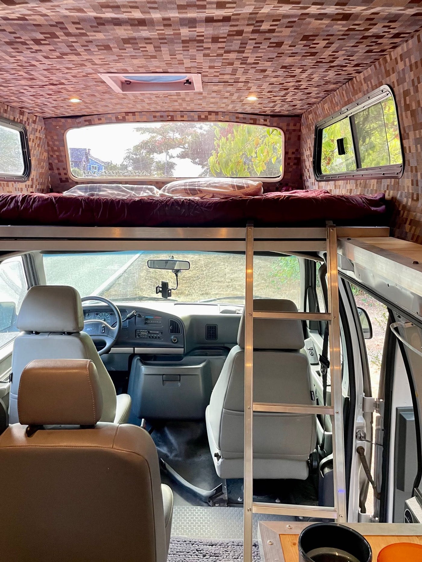  parked for night camping in a vast mountain landscape at twilight.|Silver RV rental camper van parked in a peaceful forest clearing. This off-road ready vehicle is perfect for nature camping.|Interior of an rv rental van featuring comfortable grey seating — photo 12
