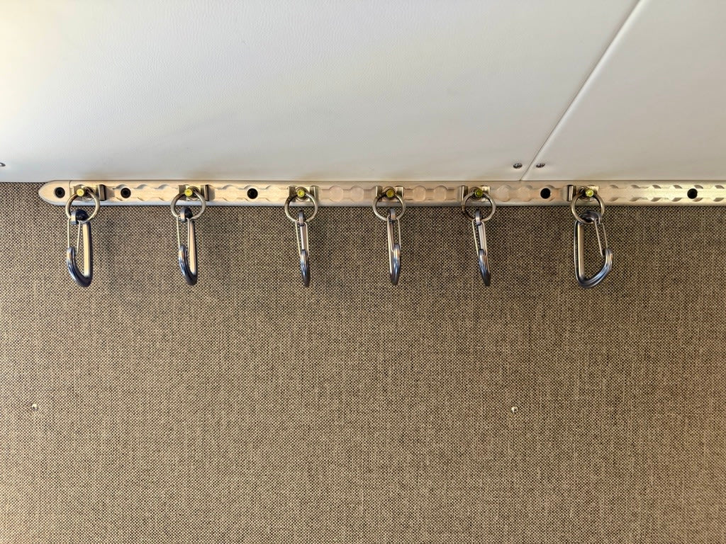 RV rental storage: Six metal carabiner hangers on a track, useful for organizing items in a compact space.