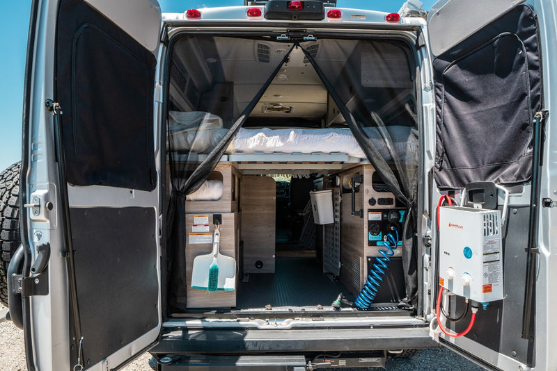 Inside a spacious RV rental camper van, featuring a cozy bed, ample storage, and a convenient hot water shower setup. — photo 10