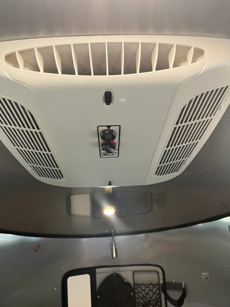 RV rental overhead view: A white AC unit with air vents and Coleman Mach controls for heating and cooling comfort.