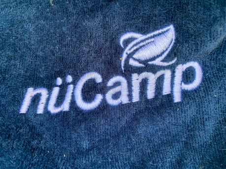 Embroidered nüCamp logo on blue fabric, showcasing quality for your next RV rental.