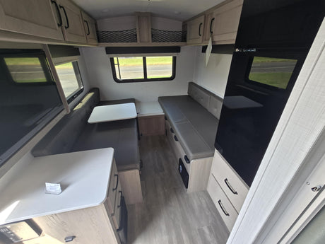Compact RV rental interior featuring a convertible dinette, sleek cabinets, and ample seating.