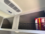 RV rental ceiling with Coleman Mach AC, overhead storage nets, and a visible first aid kit.