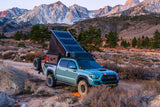 A customized overlanding Toyota Tacoma with a pop-up camper, perfect for an RV rental mountain adventure.