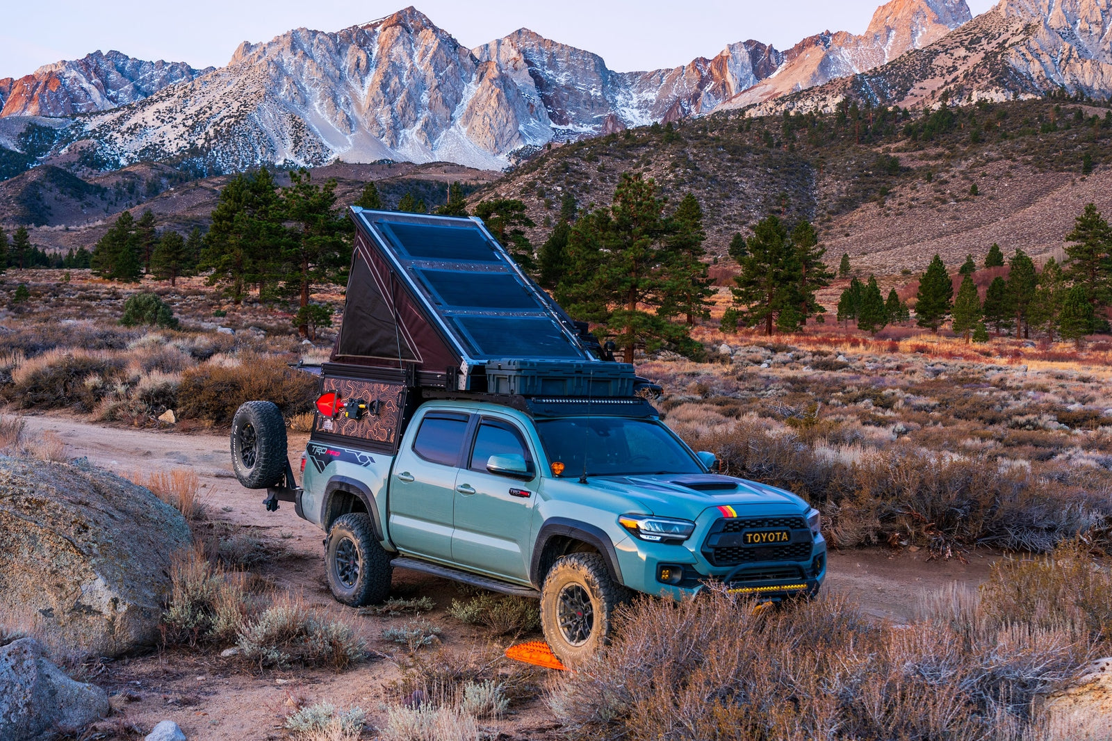 A customized overlanding Toyota Tacoma with a pop-up camper, perfect for an RV rental mountain adventure.