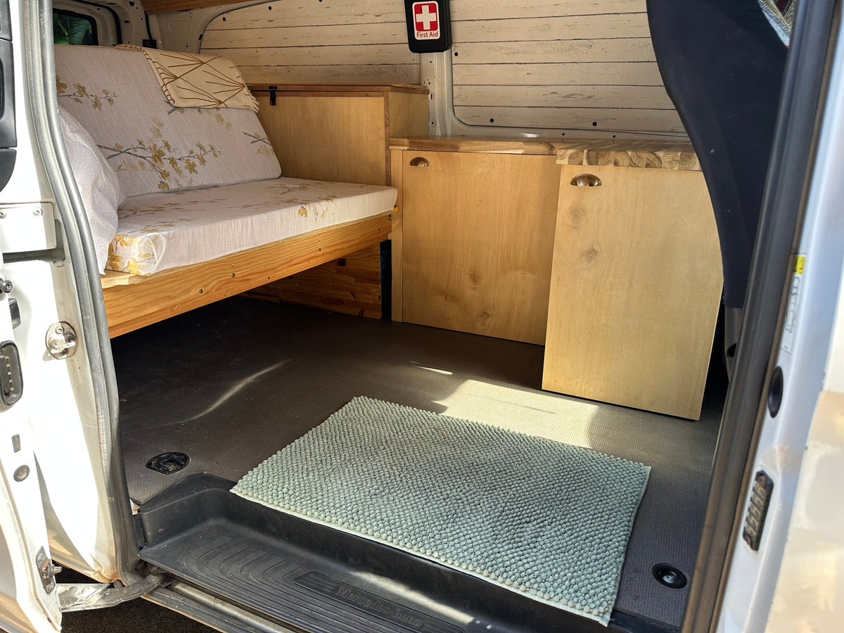 Inside a well-appointed Mercedes-Benz RV rental. Features custom bed/couch, wooden cabinets, and a neat interior. — photo 6