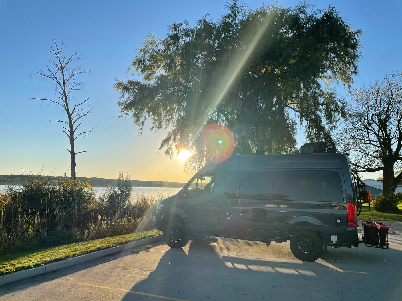 Golden hour glow on an RV rental camper van by a lake. Ideal for a scenic road trip or van life adventure.