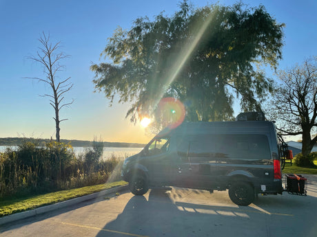 Golden hour glow on an RV rental camper van by a lake. Ideal for a scenic road trip or van life adventure.