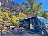 RV rental set up for glamping amidst stunning red rock mountains and vibrant autumn foliage at a scenic campsite.