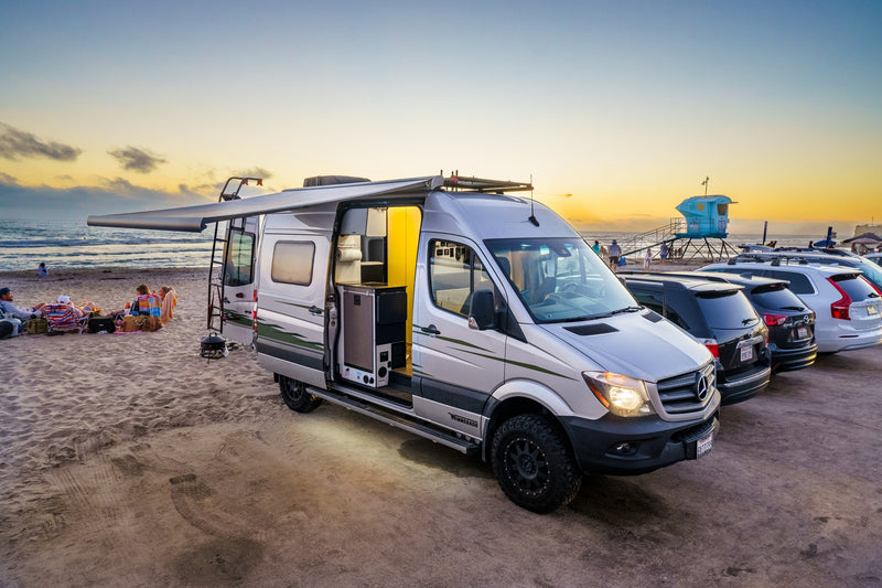 Enjoy beach sunsets with an RV rental! This silver camper van offers outdoor living by the ocean at dusk. — photo 3
