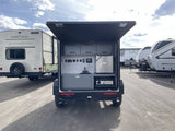 This RV rental features a compact camper with a rear outdoor kitchen, complete with a fridge, sink, and Blackstone griddle.