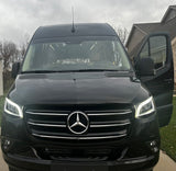 A sleek black Mercedes-Benz Sprinter luxury RV rental van. Its bright headlights and open door invite adventure.