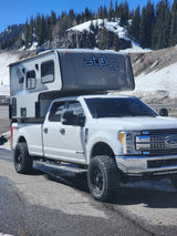 This rugged Ford Super Duty with an Atom truck camper, perfect for an RV rental adventure, is ready for mountain exploring.