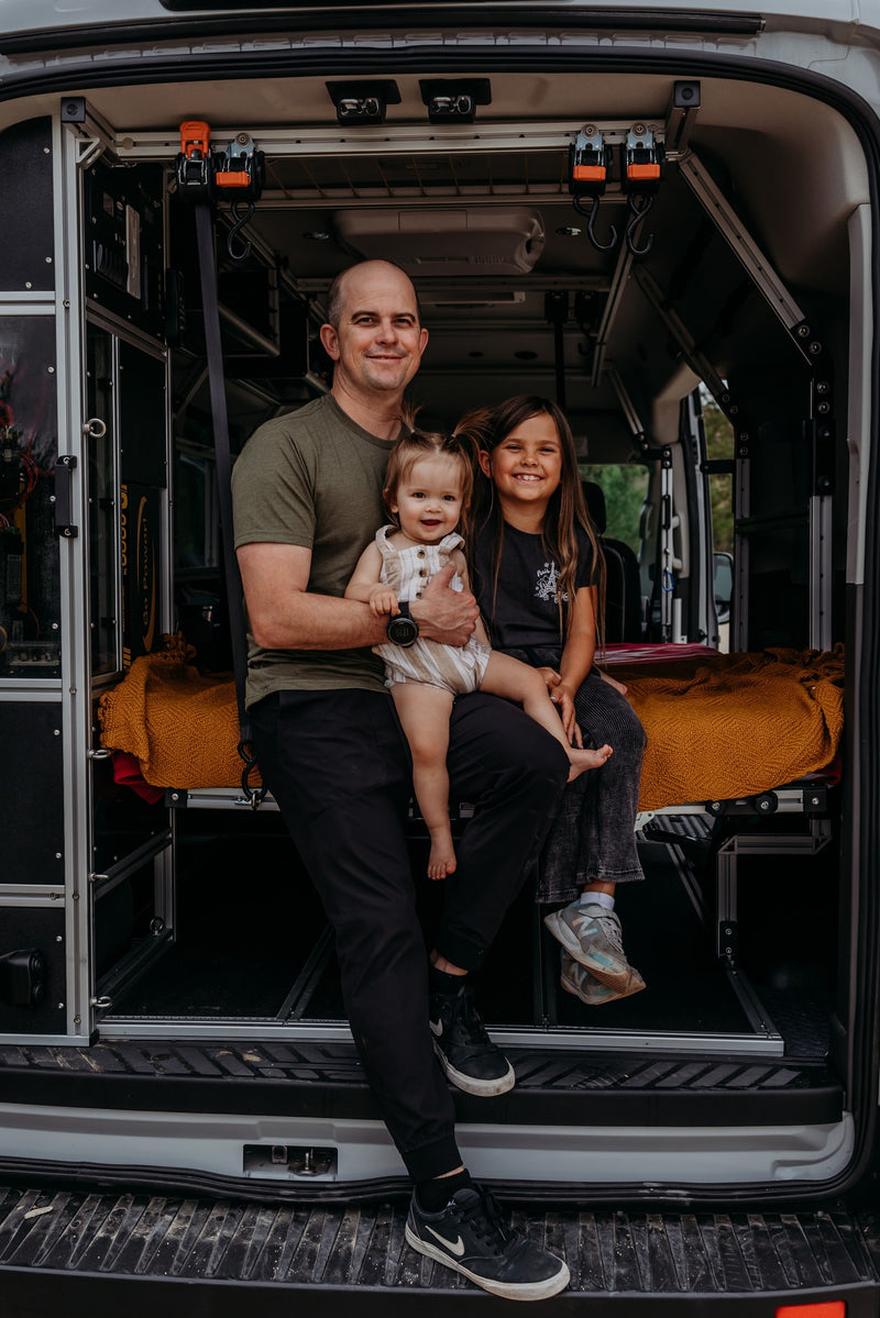 Smiling family inside a custom RV rental. A dad holds a toddler, an older child sits beside them in the camper van. — photo 5
