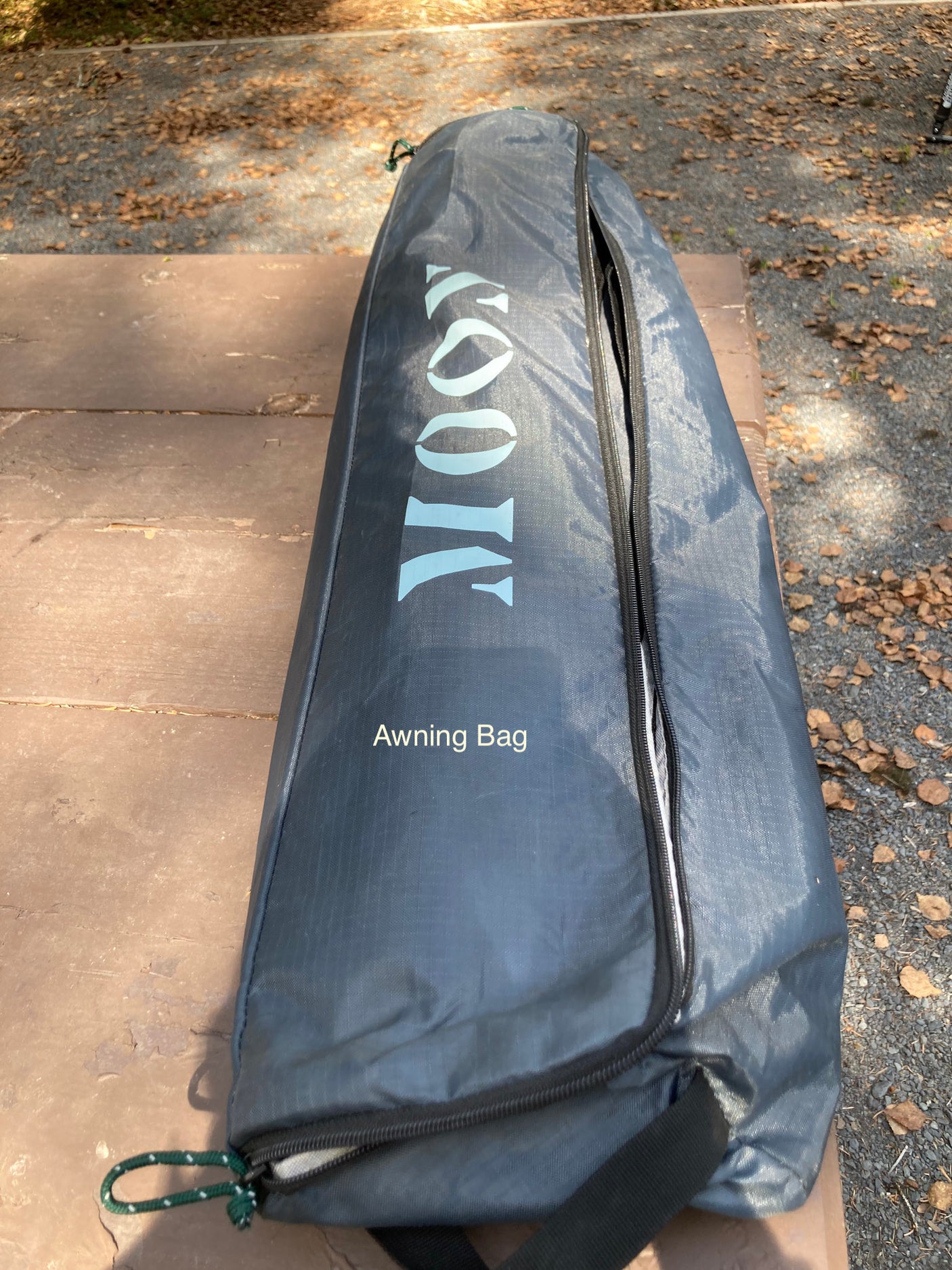 An RV awning bag, branded MOOVI, rests on a rustic picnic table—essential gear for your next RV rental adventure.