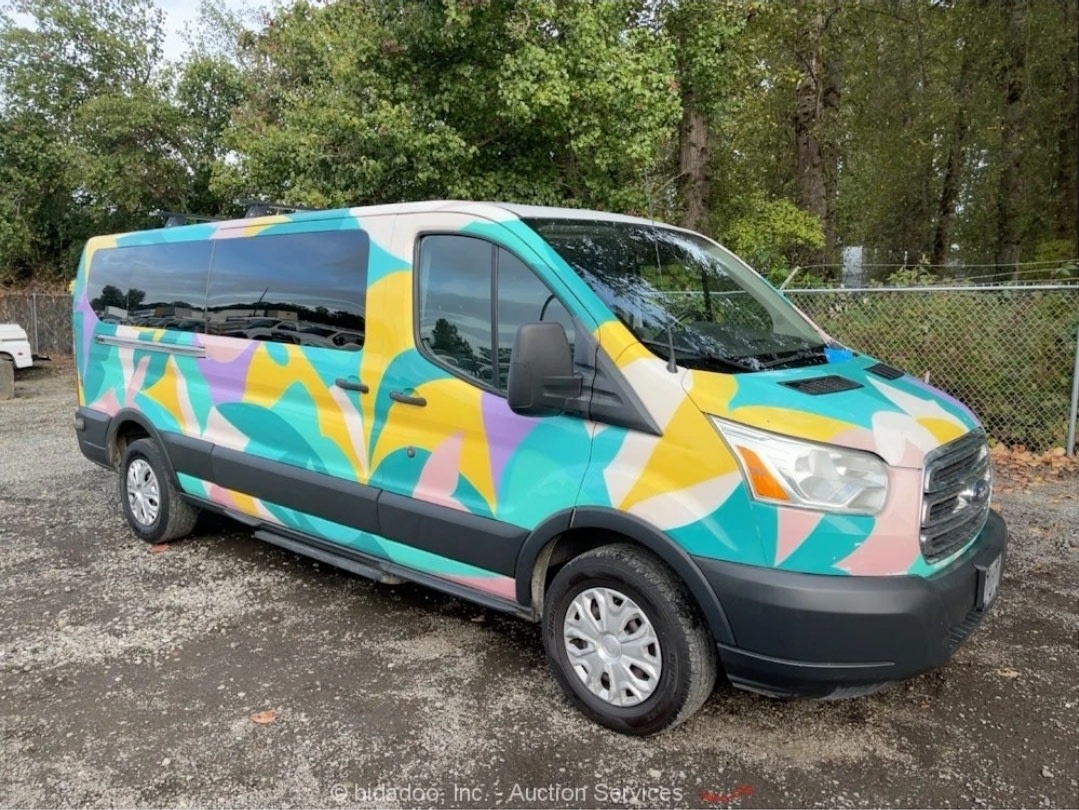 abstract-painted Ford Transit RV rental parked against a backdrop of mountains & tall trees under a bright blue sky.|Vibrant