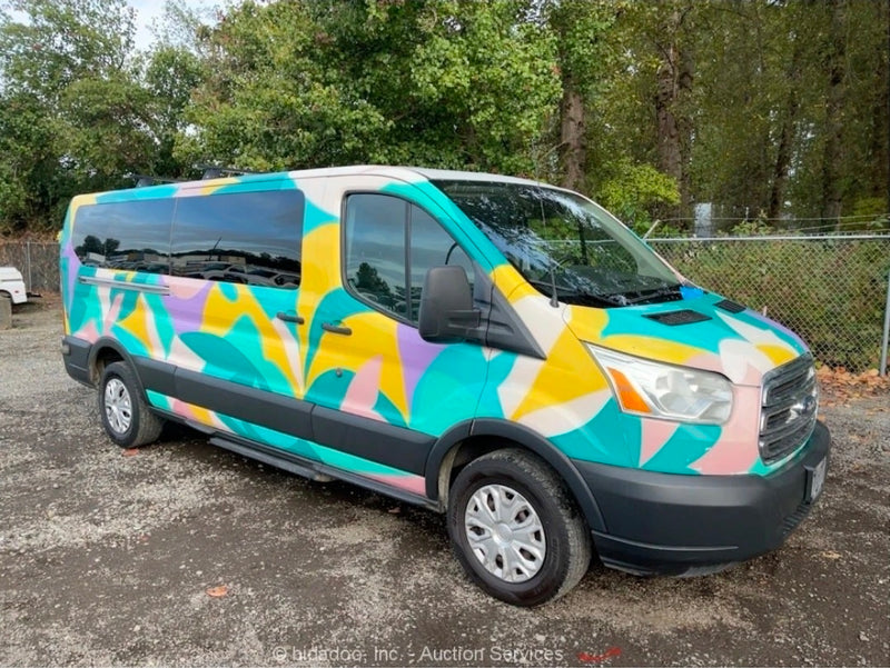  abstract-painted Ford Transit RV rental parked against a backdrop of mountains & tall trees under a bright blue sky.|Vibrant — photo 1