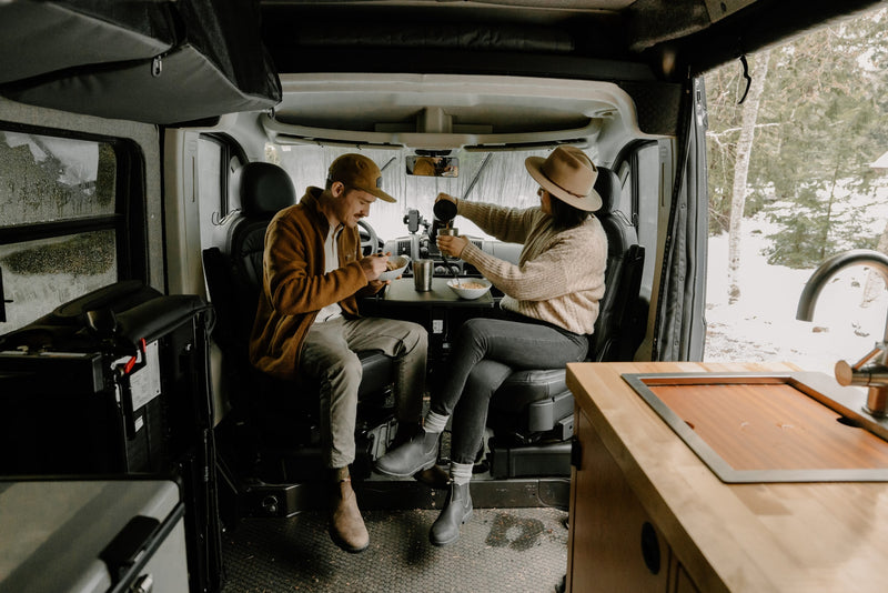  next to a French press in an RV rental.|A person in a cap and jacket steps from a grey RV rental van — photo 34