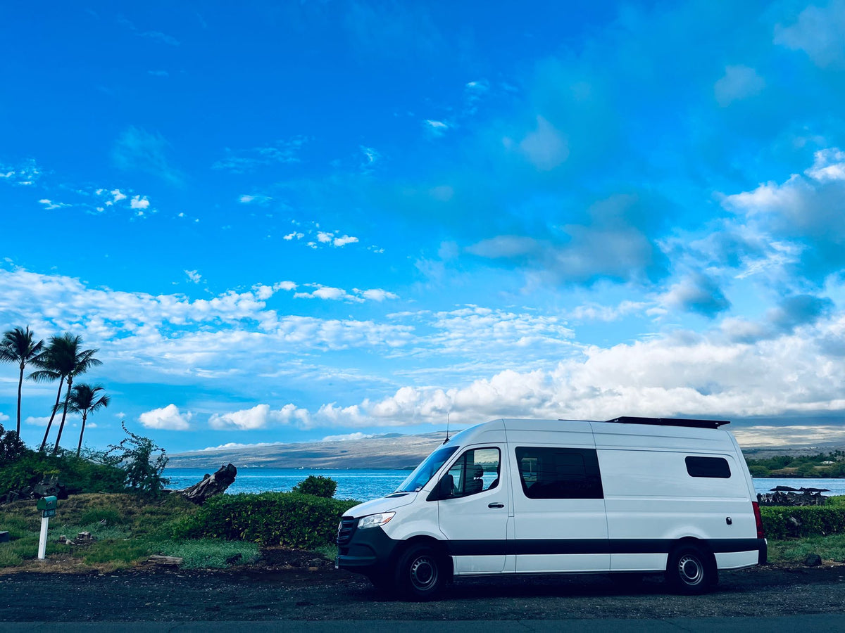  & a stunning tropical ocean view. Ideal for road trips!|White RV rental camper van parked along a scenic coastal road with blue ocean — photo 3