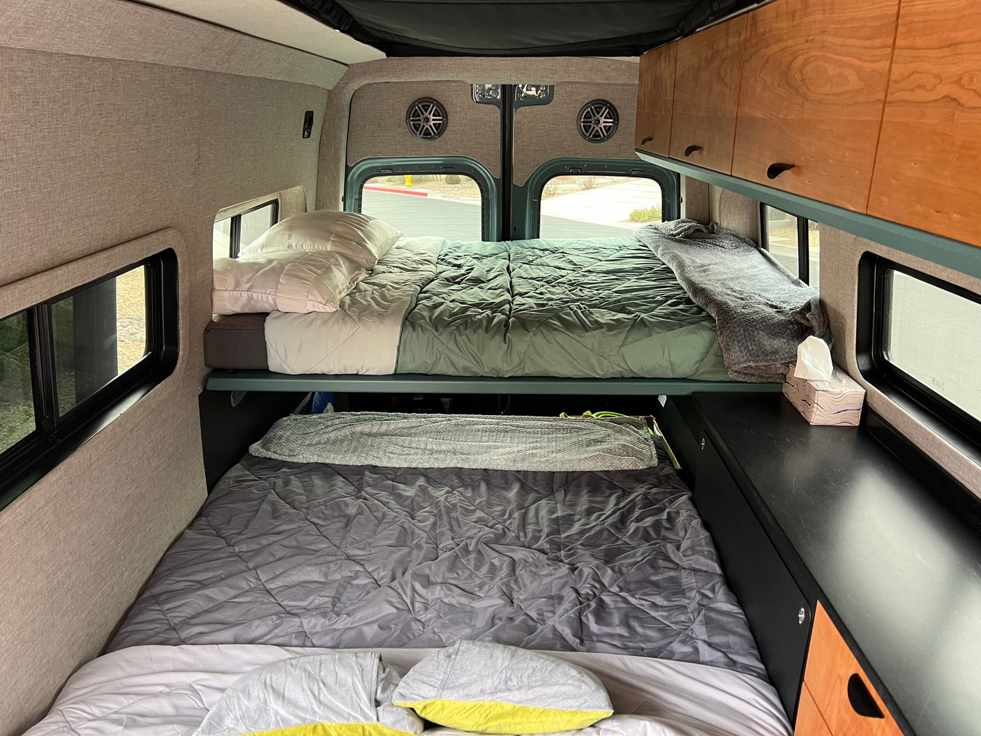 Stacked bunk beds inside an RV rental, featuring custom cabinetry and large windows for scenic views.
