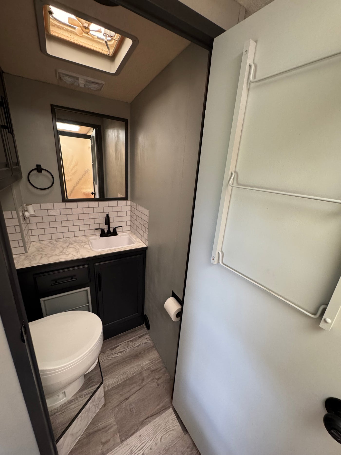 RV rental bathroom: A modern space with a white sink, toilet, mirror, subway tile, and overhead fan for comfortable travel. — photo 14