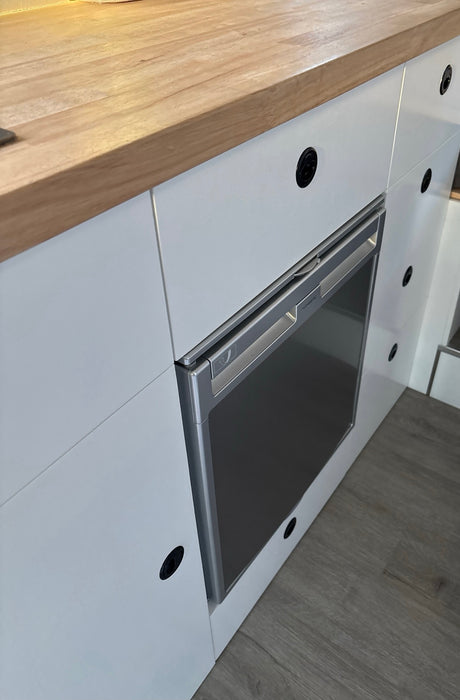 Compact fridge & wood counter in a modern RV rental kitchenette, perfect for road trips.