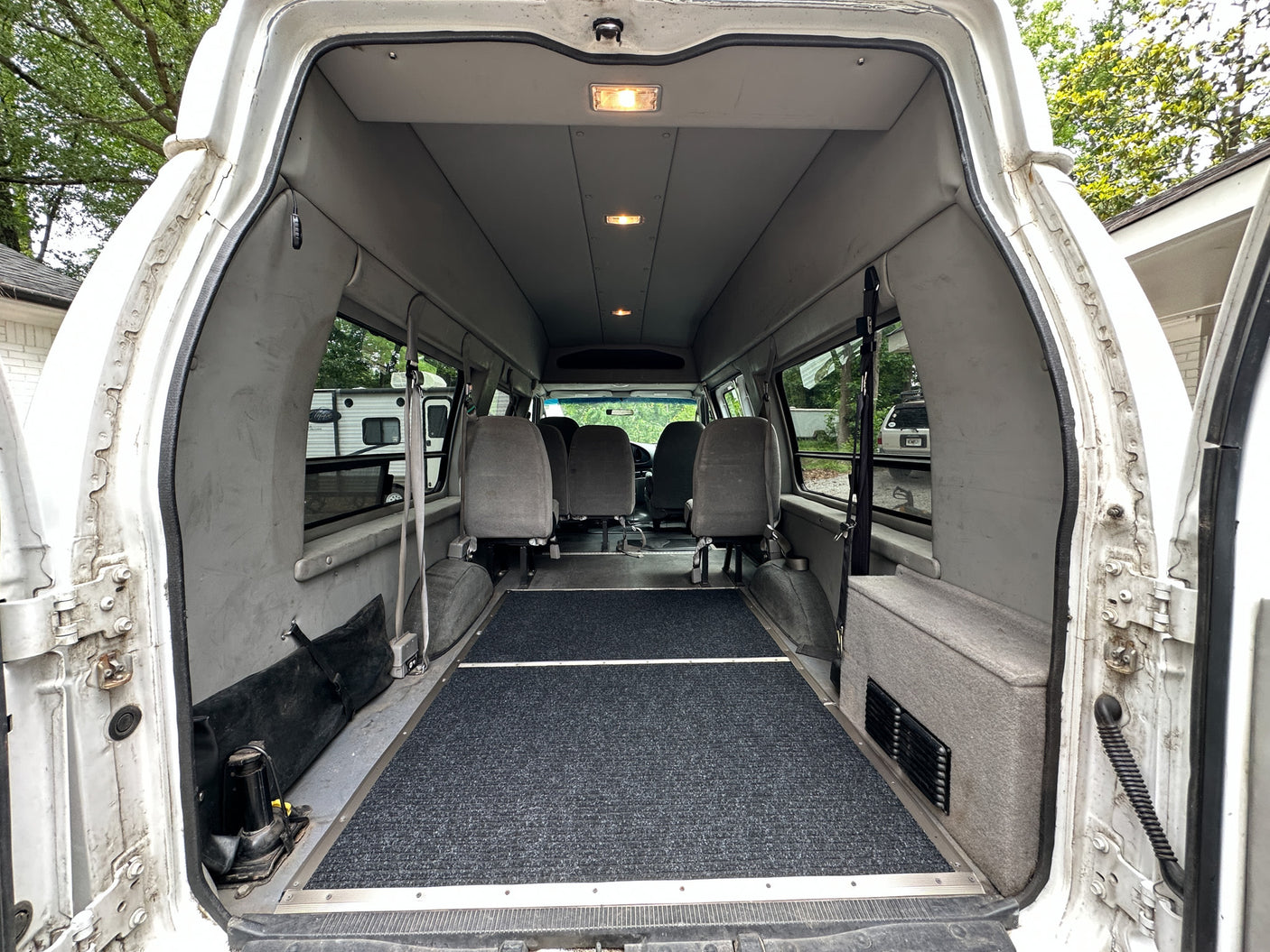 Spacious white van interior with gray seats & dark floor. Ideal for an rv rental, cargo, or passenger transport.