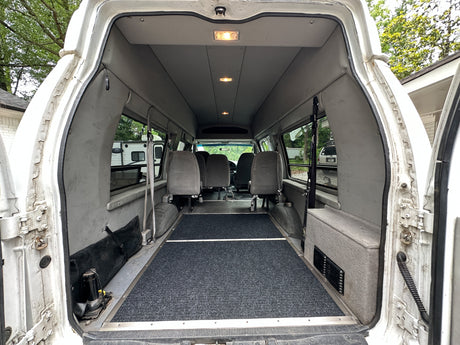 Spacious white van interior with gray seats & dark floor. Ideal for an rv rental, cargo, or passenger transport.