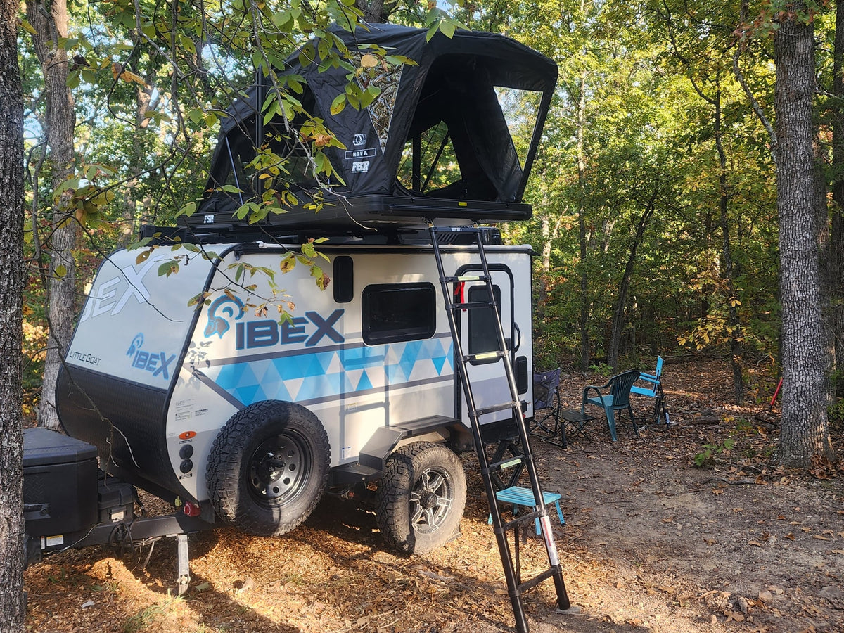 RV rental: Ibex Little Goat travel trailer with an FSR rooftop tent set up at a wooded campsite