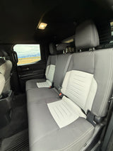 Inside your RV rental: Comfortable rear seats, two-tone gray fabric, and a scenic mountain window view.