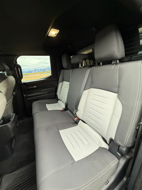 Inside your RV rental: Comfortable rear seats, two-tone gray fabric, and a scenic mountain window view.