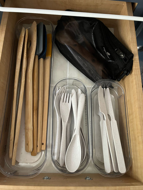RV rental kitchen drawer: Organized bamboo & silicone utensils, reusable cutlery, and an Eagle Creek travel bag.