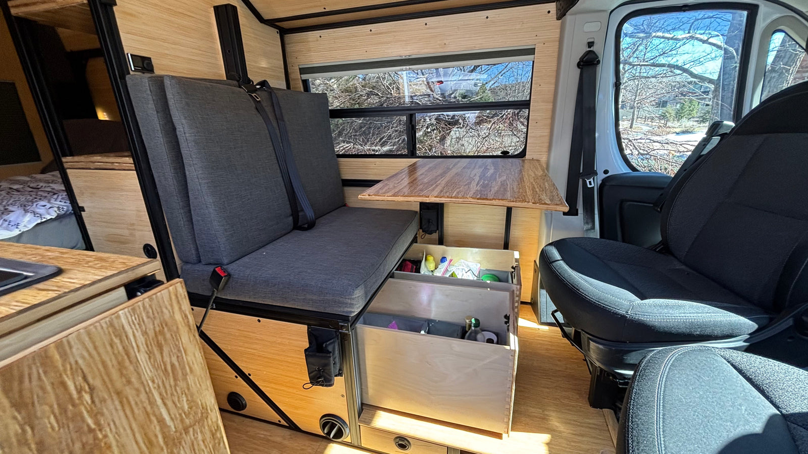 RV rental interior: Custom wood-paneled camper with a comfy bench seat, table, and practical storage drawers.