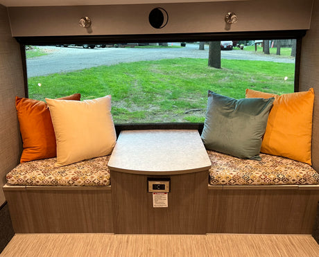 Comfortable RV rental dinette featuring plush seating, a central table, and a wide window for scenic views.