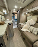 Explore this sleek RV rental: compact kitchen, comfy dinette with a plush throw, and modern amenities for your trip.