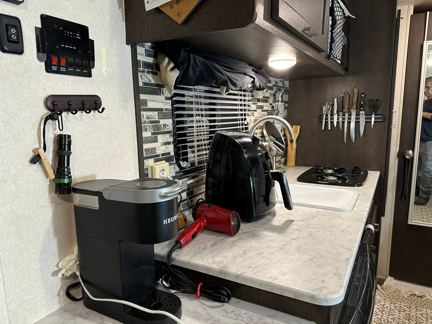 Inside an RV rental kitchen, featuring a Keurig, air fryer, stove, sink, and magnetic knife strip.